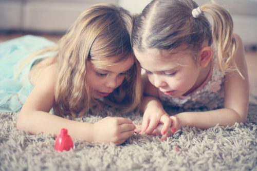 Little Girls painting nails on carpet